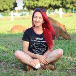 Sharon com uma de suas camisetas e as capivaras ao fundo