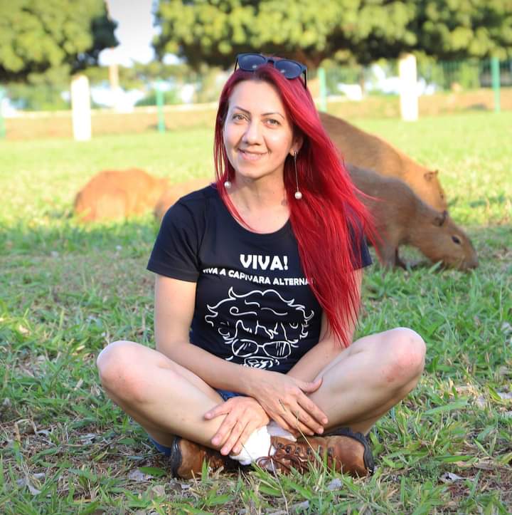 Sharon com uma de suas camisetas e as capivaras ao fundo