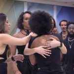 Natália sendo contida por brothers na cozinha