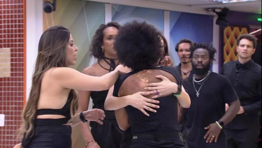 Natália sendo contida por brothers na cozinha
